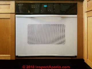 The Jenn-Air oven door glass has been repalced with a white glass front after the original black-fronted door broke. Both black and white replacement glass fronts for Jenn-Air ovens may occasionally be found online from appliance repair services (C) Daniel Friedman at InspectApedia.com