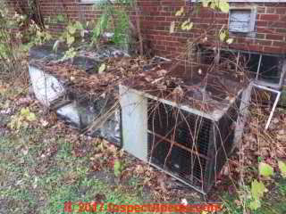 Air conditioner compressor condenser unit overgrown, damaged, out of commission, without a cover (C) Daniel Friedman