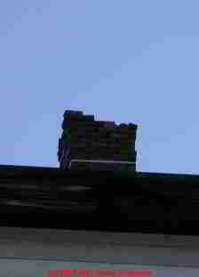 Photograph of a brick chimney missing bricks, no cap.