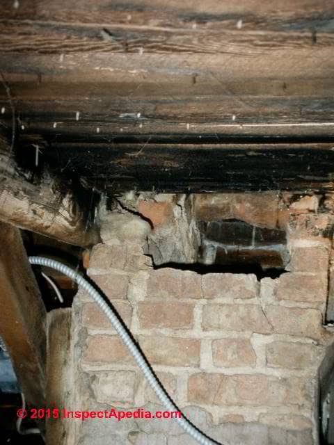 Photograph of a damaged unsafe brick chimney in an attic.