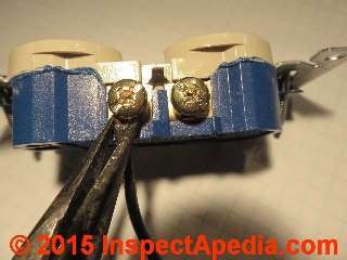 Using pliers to close a wire hooked around a screw connector on an electrical outlet (C) Daniel Friedman
