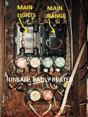 Fuse box showing terrible (unsafe) rust as well as labels for MAIN LIGHTS and MAIN RANGE (C) Daniel Friedman at InspectApedia.com