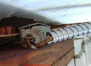 Unsafe flexible metal conduit (BX) at an electrical box (C) InspectApedia.com Mel