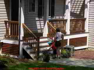 Photograph of a newly painted building exterior of an older home with small children present. Was lead paint left scattered on the ground in the play area?.