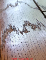 Wood floor identified as oak, not teak, with surface damage, grooved edges = factory finish (C) InspectApedia.com Coleen Maki