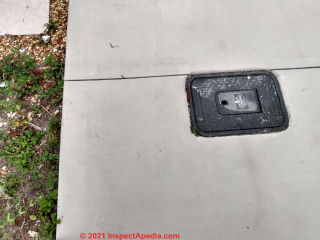 Concrete sidewalk poured over incoming water piping provides access to shutoff or meter (C) InspectApedia.coM Brison