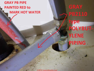 Corroded leaky PB polybutylene pipe connectors and probably red PEX, perhaps a replacement pipe, (C) InspectApedia.com BnB Home Inspections 2019