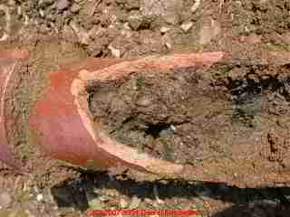 Photograph of a clogged, broken clay drain line pipe section after excavation.
