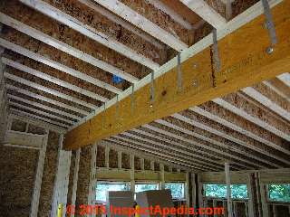 Steel strapping ties the roof beam to the wood I-trusses above © Daniel Friedman at InspectApedia.com