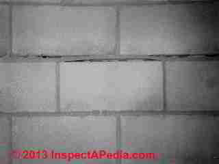 Wavy mortar indicates damage to the block foundation during backfill © Daniel Friedman at InspectApedia.com