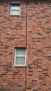 Cracks and movement in a brick veneer wall on one side of expansion joint (C) InspectApedia.com Fred Smith