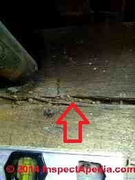 Termite mud tubes horontally located in checking splits in a wood beam (C) InspectAPedia - GM