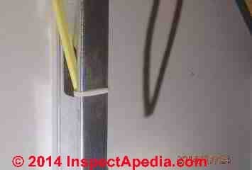 Unprotected NMC wiring passing through a metal stud violates electrical code (C) InspectApedia Bob Sisson