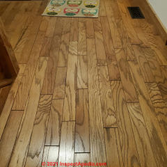 Wood floor identified as oak, not teak, with surface damage, grooved edges = factory finish (C) InspectApedia.com Coleen Maki