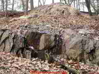 PHOTO of a failed drainfield leaking across rock on a steep site.
