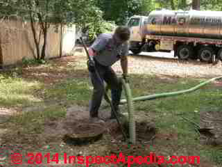 Septic tank cleaning showing use of the hoe or rake to get up the sludge (C) Daniel Friedman