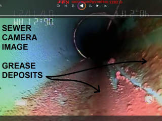 Grease deposits in a sewer line, revealed by a sewer line camera inspection (C) InspectApedia.com DovBer Kahn