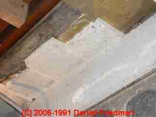 Photograph of  LARGER IMAGE - asbestos slab ceiling insulation, tremolite asbestos showing exposed ends projecting over a basement partition